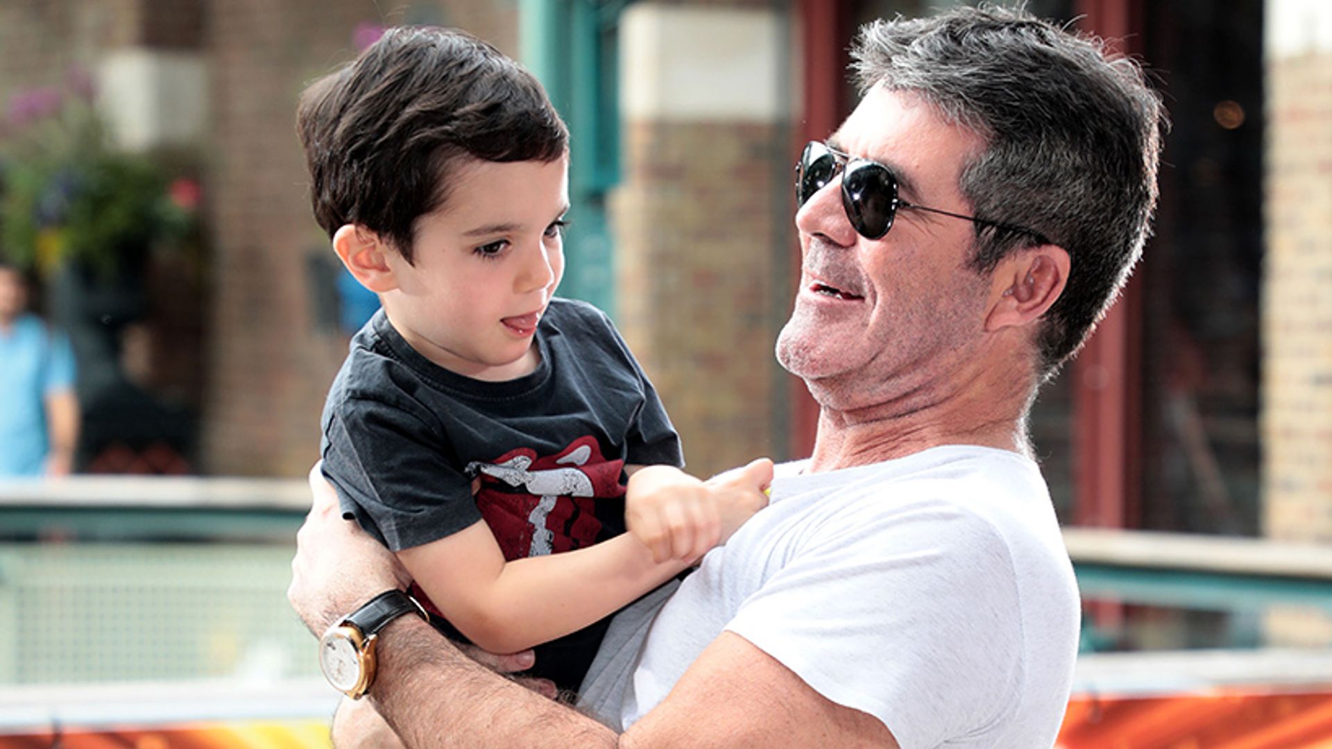 Simon Cowell carrying his son in his arms