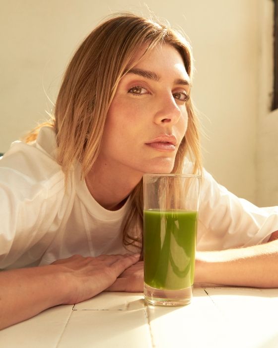 valentina ferrar leans chin on glass of green juice